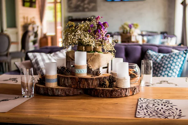 candles in restaurant decor. candle and pine cones. Decorative white candles stand on a slice of wood. the country house decor is in the details.white - pink heather in autumn basket. wedding table. Copy space