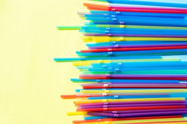 Pastel arka planda çok renkli plastik pipetler. İçme suyu veya meşrubat için kullanılan plastik pipetler. Protesto kavramı. Sarı arka planda plastik yok. Renkli tasarım ve soyut