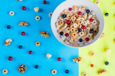 Sağlıklı kahvaltı ve atıştırmalık konsepti, taze ahududu ve fındık ve granola barları, parlak mavi ve sarı arka planda. kopyalama alanı. Üst görünümde kusursuz desen. Yuvarlak şekilli gevrek taneleri..