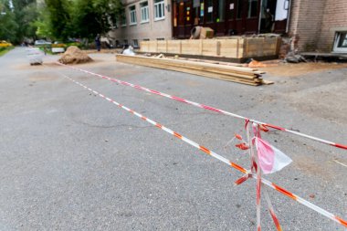 Tamir sırasında tehlikeli yerleri çitlemek için bürokrasi ve beyaz bant. Apartmanın etrafındaki bölgenin onarımı. Tamir için çit, kırmızı şeritli uyarı bandıyla eskrim.