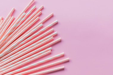 Striped drink straws of different colors in row isolated on yellow background. Minimalism concept. Pop art style. Flat lay with straws. Birthday Party Celebration Kids Fun. Greeting Card Poster