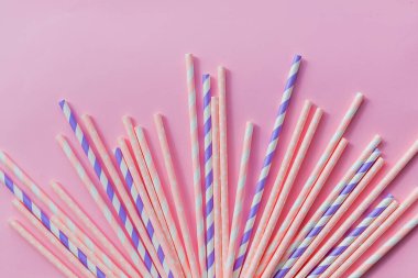 Striped drink straws of different colors in row isolated on yellow background. Minimalism concept. Pop art style. Flat lay with straws. Birthday Party Celebration Kids Fun. Greeting Card Poster