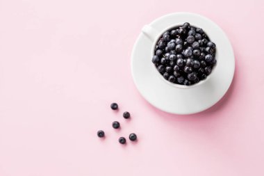 Beyaz bardakta yabanmersini. Sulu ve taze yaban mersinli çanak çömlek. Uzayı kopyala. Pembe arka planda taze böğürtlenli bardak. Taze meyve topluyorum.