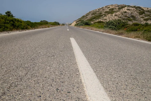 Close-up de linha divisória na estrada de asfalto no verão. linhas brancas na estrada rodoviária vazia com colinas, monte. linha surface.white estrada na estrada de asfalto fechar e céu azul claro. Conceito de viagem. Vista de — Fotografia de Stock