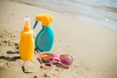 Güneş kremi, kumsalda gözlük. Güneş yanığı için kozmetik. Deri bakımı konsepti. Tatilde sağlıklı cilt. Mutlu ve sağlıklı tatiller için seyahat aksesuarları. Güneş gözlüğü, güneş kremi.