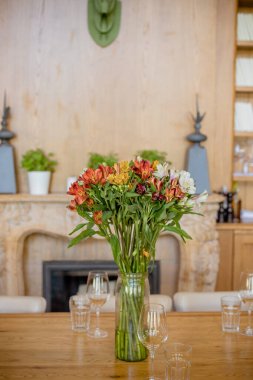 Yumuşak arka planda güzel bahar çiçekleri. Alstromeria buketi, vazoda sarı merkezli taze parlak çiçekler. Ev dekorasyonu. Şöminenin arkasında renkli bir buket. Dikey görüntü.