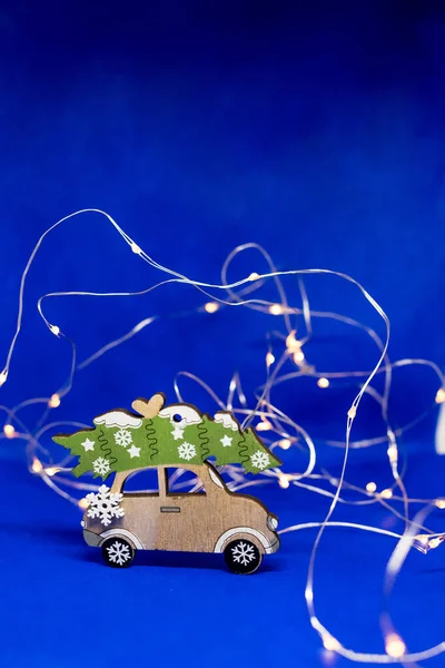 Рождественская игрушечная машина с рождественской елкой на синем фоне, с garland.wooden винтажный автомобиль .Christmas или Новый год минимальный concept.Miniature car.Holiday background.Happy нового года. Копирование пространства — стоковое фото