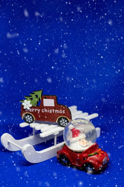Auto rossa con Babbo Natale. giocattoli su sfondo blu con spazio copia e decorazione di Natale. Babbo Natale e giochi in legno.Natale creativo e biglietto di auguri di Capodanno con effetto neve.Atmosfera magica — Foto Stock