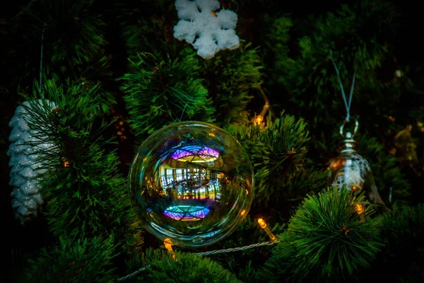 Grote transparante decoratieve bal op kerstboom. Feestelijk concept. Kleurrijke reflectie.Kerst speelgoed, glazen bal opknoping op een groene kerstboom tak. Magische sfeer.Prachtige kerst — Stockfoto