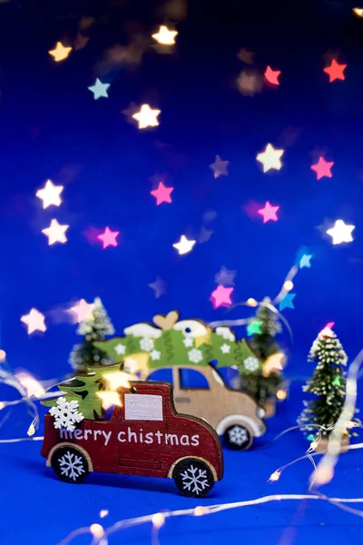 Маленький красный деревянный игрушечный автомобиль на синем фоне с блестками на заднем плане. Концепция празднования Рождества и Нового года. Праздничное оформление и фон для поздравления с копией space.Creative — стоковое фото