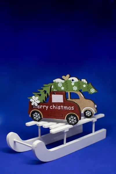 Árvore de Natal no trenó de madeira, Natal festa concept.Merry Natal e Feliz Ano Novo cartão de saudação. árvore de férias, carro de brinquedo de madeira no fundo azul com espaço de cópia. — Fotografia de Stock