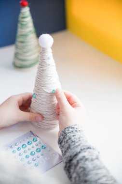 Çocuk Noel ağacı süslemesi gösteriyor. Yaratıcı el yapımı Noel ağacı yapmak. Çocuklar ölür konsepti. Xmas oyuncakları dekorasyonu. Oyuncağı yapay elmasla süsle. Çevre dostu Noel ağacı.
