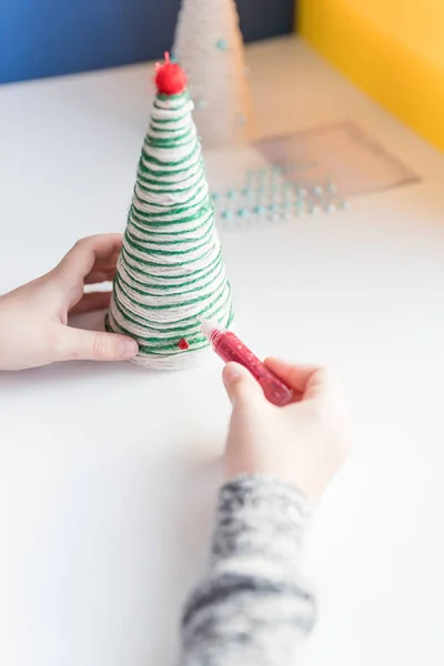 Çocuk Noel ağacı süslemesi gösteriyor. Yaratıcı el yapımı Noel ağacı yapmak. Çocuklar ölür konsepti. Xmas oyuncakları dekorasyonu. Oyuncağı yapay elmasla süsle. Çevre dostu Noel ağacı.