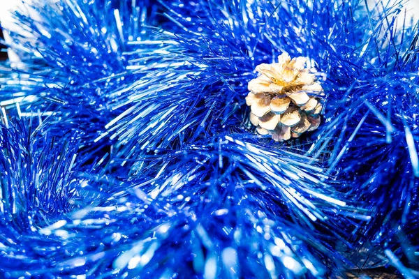 輝く抽象的な青のボケの背景.tinsel 、クリスマスと新年の装飾、青の背景に隔離された松のコーンで装飾、トップビュー。クリスマスの装飾の松。挨拶 — ストック写真