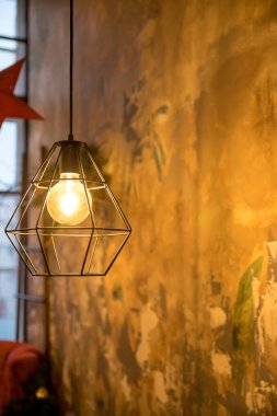 Endüstriyel tel lamba. Çokgen avize. Parlak ışıklar ve karanlık arka plan. Çatı katı tarzı iç mekan. Grunge dekorasyonu. Moda tasarımı. Tavanda romantizm için asılı eski ve klasik siyah lamba.