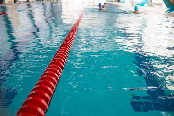 Swimming pool lanes in competition pool.red plastic rope lane on blue water indoor swimming pool sport competition background.Selective focus.