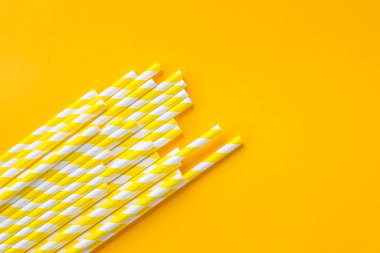 Kokteyl pipetleri sıra soyut arkaplanda. Sarı arka planda çok renkli meyve suyu pipetleri var. Boşluğu kopyala, üst görünüm. Boşluğu kopyala. Geri dönüşüm, çevre dostu malzemeler. Çelme takılmış içecek pipetleri.