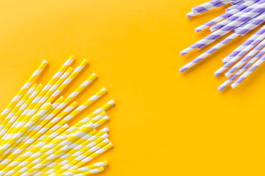 Kokteyl pipetleri sıra soyut arkaplanda. Sarı arka planda çok renkli meyve suyu pipetleri var. Boşluğu kopyala, üst görünüm. Boşluğu kopyala. Geri dönüşüm, çevre dostu malzemeler. Çelme takılmış içecek pipetleri.