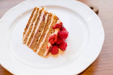 sweet honey cake decorated with raspberry,berries on white plate.fresh cake with red raspberries. Delicious Dessert for tea. fresh Raspberry cake. Homemade berries cake. Copy space. Selective focus.