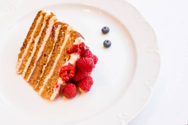 sweet honey cake decorated with raspberry,berries on white plate.fresh cake with red raspberries. Delicious Dessert for tea. fresh Raspberry cake. Homemade berries cake. Copy space. Selective focus.