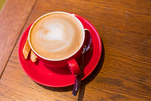 Coffee-break. Red cup of cappuccino with beautiful latte art on old wooden background. Latte art coffee.aroma coffee in red ceramic cup. Copy space.wood table in cafe, restaurant — Stock Photo, Image