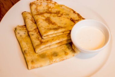 Crepes with sour cream on white plate , copy space. Delicious homemade Crepes for breakfast.Thin three crepes or pancakes with butter, honey and sour cream.Delicious breakfast or brunch