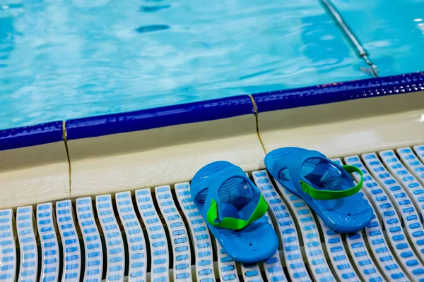 Flip Flops on the pool, summer background with copy space.Summer vacation at a resort.Summer accessories at the swim pool, Travel concept, Vacation time.Slippers, Pair of kids blue flip-flops