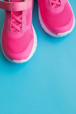 Pembe çocuklar mavi arka planda izole edilmiş spor ayakkabıları. Çocuk giyimi, ayak giyimi ve moda. Çocuklar için spor ayakkabıları. Boşluğu kopyala