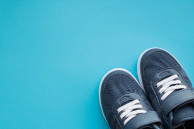 Çocuklar için spor ayakkabıları mavi arka planda izole edilmiş. Arka planda günlük ayakkabılar. Ayakkabılar öncelikle spor ya da diğer spor türleri için tasarlanmıştır. Mavi ayakkabılar.