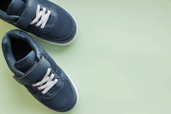kids athletic shoes isolated on pastel green background.Pair of casual shoes on color background.Sneakers are shoes primarily designed for sports or other forms of physical exercise.Blue shoes.Copy