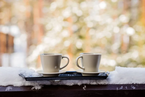 Relajante y beber café o té, sentado en la luz del sol disfrutando de café por la mañana.dos tazas de café en un día soleado, en balkony. concepto de relajación. fondo borroso de hermosos paisajes en el — Foto de Stock