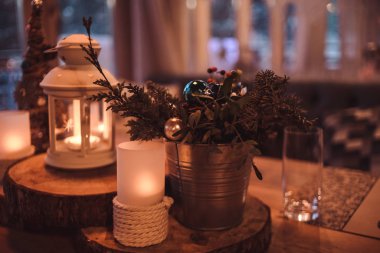 Noel ya da yeni yıl partisi masası. Ton görüntüsü. Şenlikli akşam yemeği konsepti. Şenlikli şube dekorasyonu, mumlar ve kırsal ahşap masa zemininde parlayan oyuncaklar. Kış