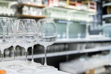 Mağazada satılık modern bardak rafları. Bardaklar ve kadehler. Bir mağazanın cam rafında tasarım cam eşyalar. Masa gereçleri. Modern ev dekorasyonu mağazası. Perakende alışverişi