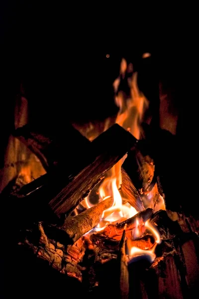 Three burning billets in hot stove.Fire flame burning coal and wood in fireplace.Hot coals in the fire.Flames of a campfire in the night.Toned image — Stock Photo, Image