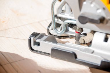 Yakın plan marangoz elektrikli testereyle çalışıyor. Adam elektrikli testereyle odun kesiyor. Ahşap işçiliği için elektrikli bir alet. Gelecekteki ürünlerin tahta parçalarını kesiyorum. Marangozluk atölyesinde çalışıyorum..