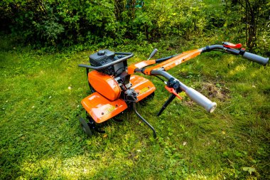 garden with tiller machine. Garden tiller to work, close up.Abstract and conceptual of motor hoe at work. garden with rototiller , tiller tractor, cutivator, miiling machine. Man plowing the garden