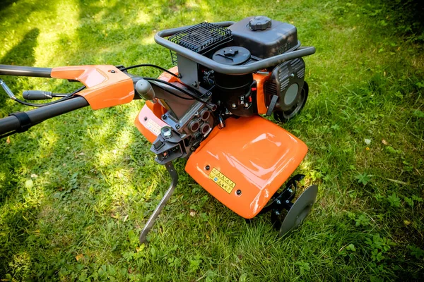 garden with tiller machine. Garden tiller to work, close up.Abstract and conceptual of motor hoe at work. garden with rototiller , tiller tractor, cutivator, miiling machine. Man plowing the garden