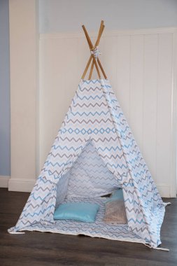 Childens room corner with a beautifully decorated play tipi tent and a pillows.Cozy play tent for kids as element of nursery interior.kids wigwam.Decorative boho styled cozy hut with decor.