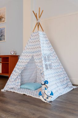 Childens room corner with a beautifully decorated play tipi tent and a pillows.Cozy play tent for kids as element of nursery interior.kids wigwam.Decorative boho styled cozy hut with decor.