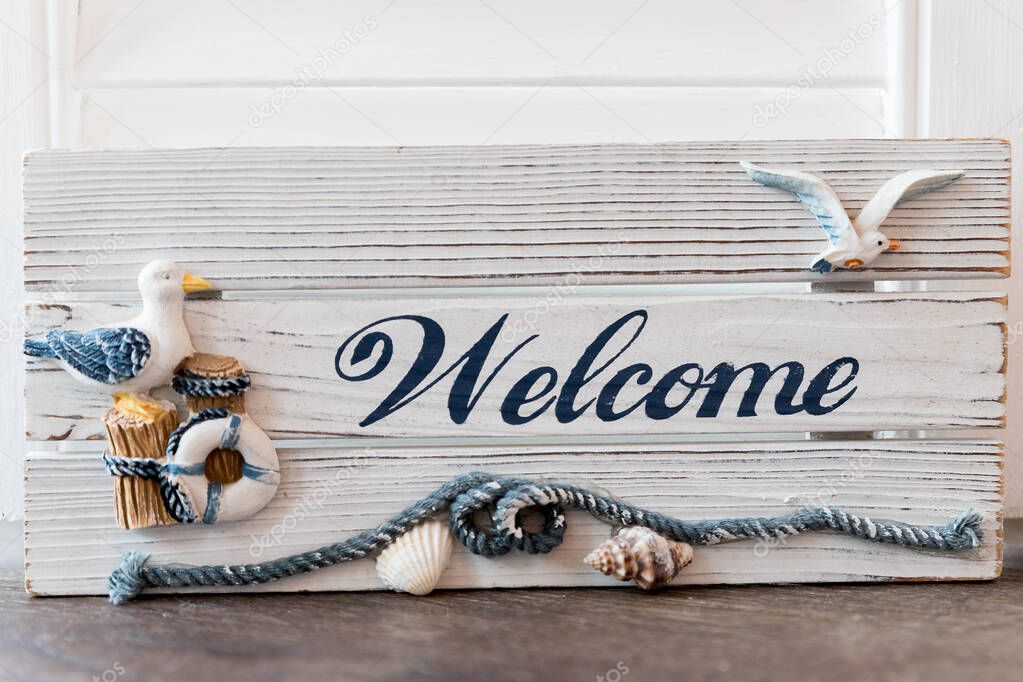 Welcome sign on antique rustic wooden sign with sea birds, Anchor and lifebuoy decoration.composition with gull, seagull and sea shells.marine still life with the word welcome.marine concept