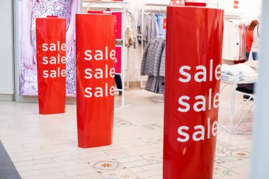 Sale Sign In A Clothing Store.Red bright sale banner on anti-thieft gate sensor at retail shopping mall entrance. Seasonal discount offer.department store for shopping, business fashion and