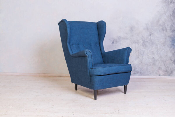 Classic blue chair. loft interior.Comfortable armchair against concrete wall background.Scandinavian style.Minimal Modern Furniture Recliner Object in Elegance Interior. Living Room Fashion Design