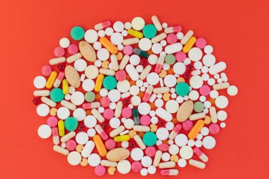 Besin takviye kapsülleriyle bileşim. Çeşitli ilaç kapsülleri. Bakım, ilaç, tedavi için vitaminler. Hastalıklar için renkli haplar, kırmızı arka planda narkotik ilaçlar..