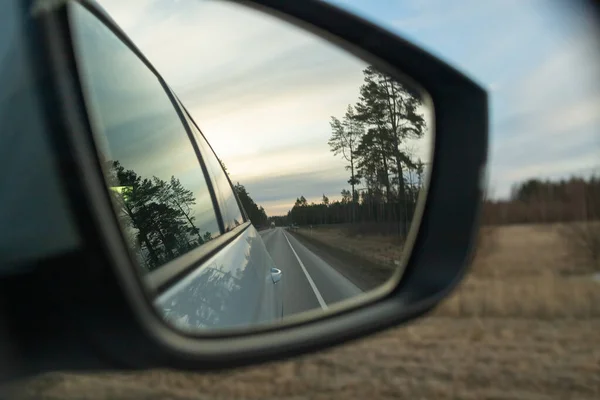 Spiegelung der Autobahn im Autospiegel. Getöntes Foto. Straßenverkehrskonzept. Autofahren bei Sonnenuntergang.Schönheit am Himmel, die nachts auf Reise geht.Reflexion der Straße im Sonnenuntergang Sonnenlicht verschwommen — Stockfoto