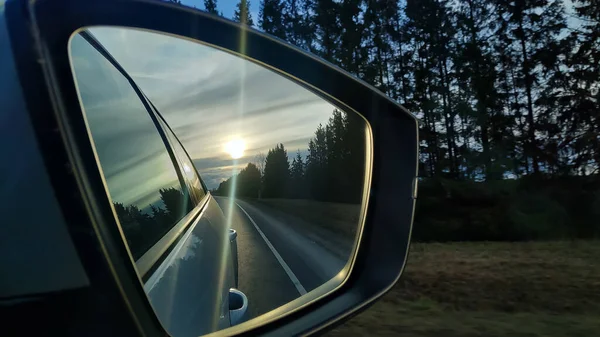 Reflexão da rodovia em um espelho de carro. Foto afiada. Road travel concept.Driving carro ao pôr do sol.Beauty no céu indo em viagem à noite.Reflexão da estrada ao pôr do sol embaçado — Fotografia de Stock