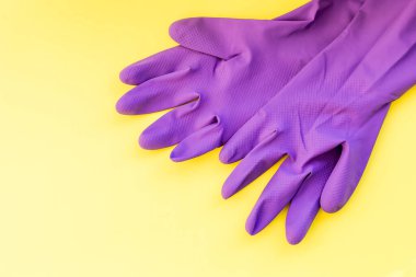 Sarı arka planda izole edilmiş temizlik ekipmanları, mor lastik eldivenler, temizlik aletleri. Temizlik konsepti, üst düzey görüş. Koruyucu lastik eldivenler. Hijyen önleme temizliği.