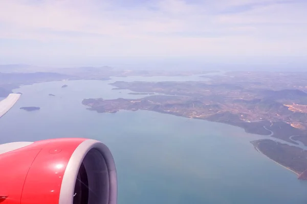 Vista aérea do avião voando acima de nuvens de sombra e céu. A asa do avião sobrevoa a ilha tropical. Vista da janela plana do momento emocional durante viagens internacionais ao redor do mundo.Ilhas — Fotografia de Stock