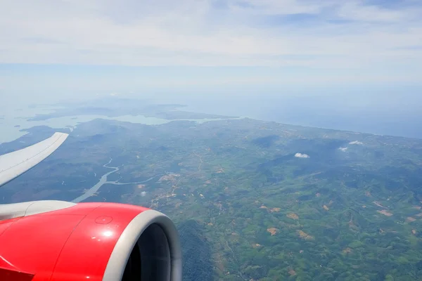 Vista aérea del avión volando por encima de las nubes de sombra y el cielo. El ala del avión vuela sobre la isla tropical. Vista desde la ventana del avión del momento emocional durante los viajes internacionales alrededor del mundo.islas —  Fotos de Stock