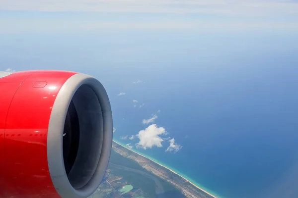 Vista aérea del avión volando por encima de las nubes de sombra y el cielo. El ala del avión vuela sobre la isla tropical. Vista desde la ventana del avión del momento emocional durante los viajes internacionales alrededor del mundo.islas —  Fotos de Stock