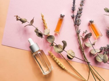 Pastel arka planda bitkisel yağ ve lavanta çiçekleri. Lavantalı bir şişe gerekli yağ. Lavander yağı. Lavanta ve portakallı doğal kozmetik ürünleri. Ev yapımı spa için limon.